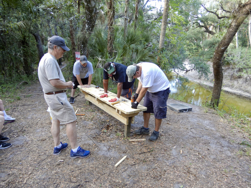 Volunteers screwing down the new bench boards with the Alafia River in the background