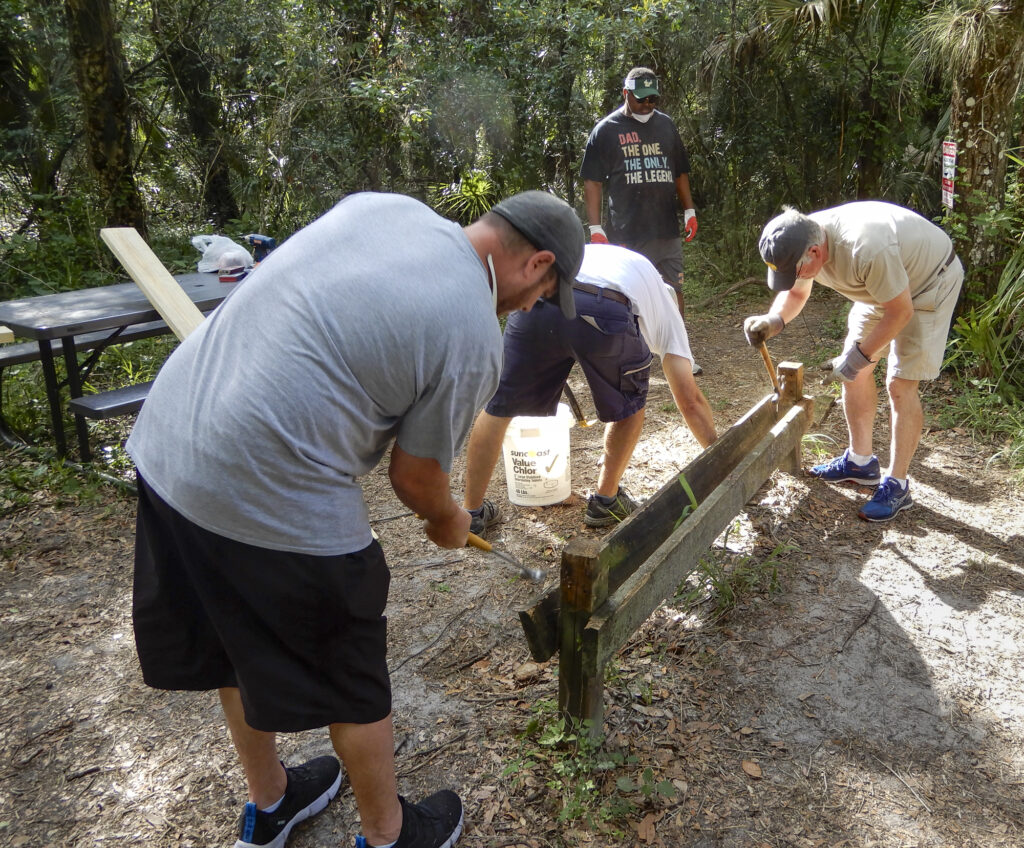 Volunteers removing the old bench posts with hammers