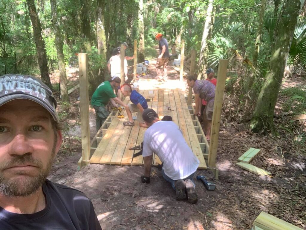 Full volunteer crew laying and screwing down the new bridge decking together
