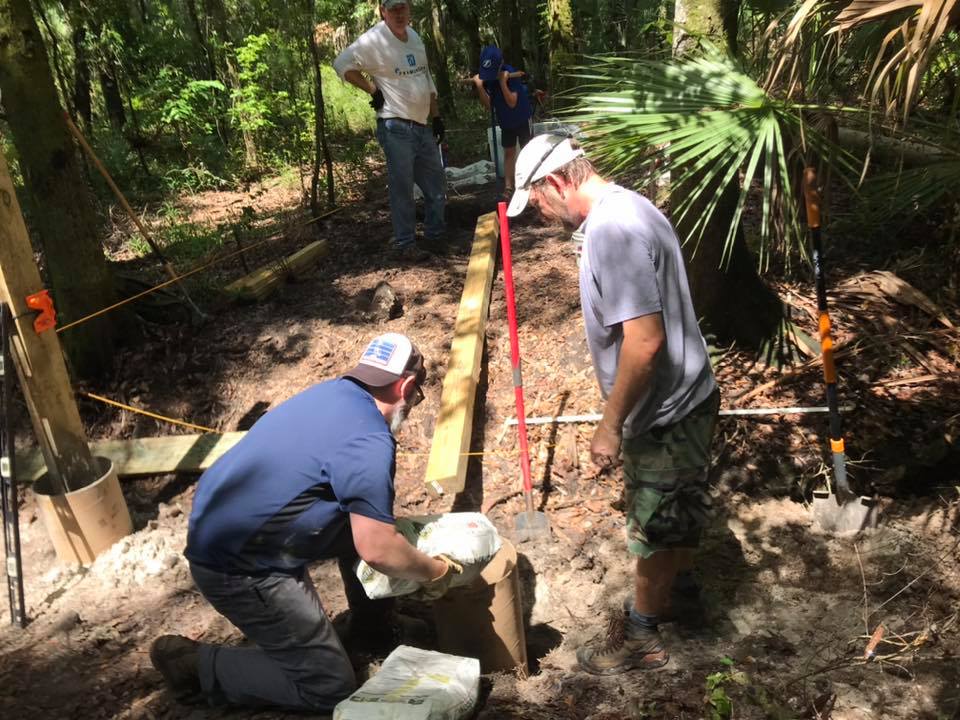 Volunteers setting posts in concrete to anchor the new bridge structure