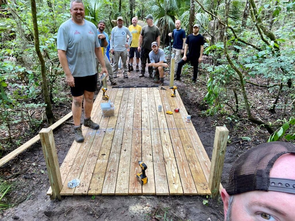 Large volunteer crew posing on the freshly decked Bridge #2 mid-construction selfie