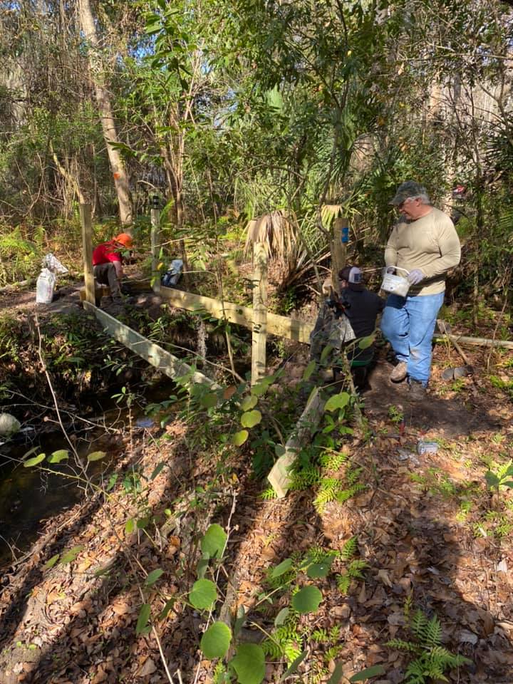 Volunteers setting the first posts and frame for Cordgrass Bridge over the creek