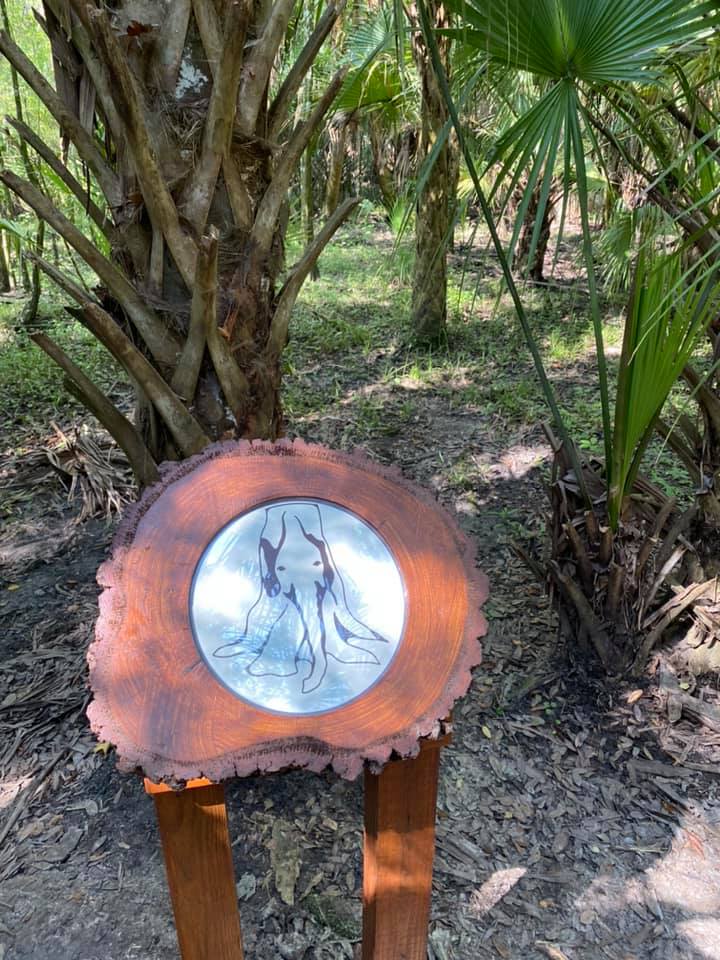Wood-burned Elephant Man Tree marker sign — a round wood slice with an etched elephant drawing on a metal disc
